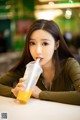 A woman sitting at a table with a drink in her hand.