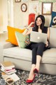 A woman sitting on a couch using a laptop computer.