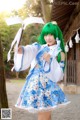 A woman in a blue and white dress holding an umbrella.