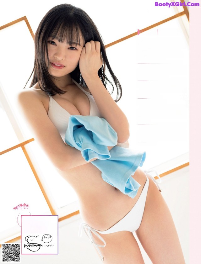 A woman in a white bikini holding a blue towel.