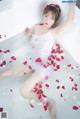 A woman laying in a bathtub filled with rose petals.