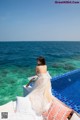 A woman in a wedding dress sitting on the edge of a swimming pool.