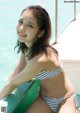 A woman in a striped bikini sitting on a boat.