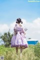 A woman in a purple dress walking through a field.