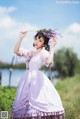 A woman in a purple dress holding a bunch of lavender.