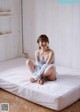 A woman sitting on top of a white bed.