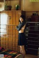 A woman standing in front of a dresser in a bedroom.