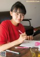 A young woman sitting at a table writing in a notebook.