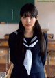 A woman in a school uniform standing in front of a blackboard.