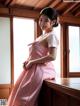 A woman in a pink dress sitting on a window sill.