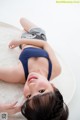 A young girl laying on a white rug with her hands on her head.